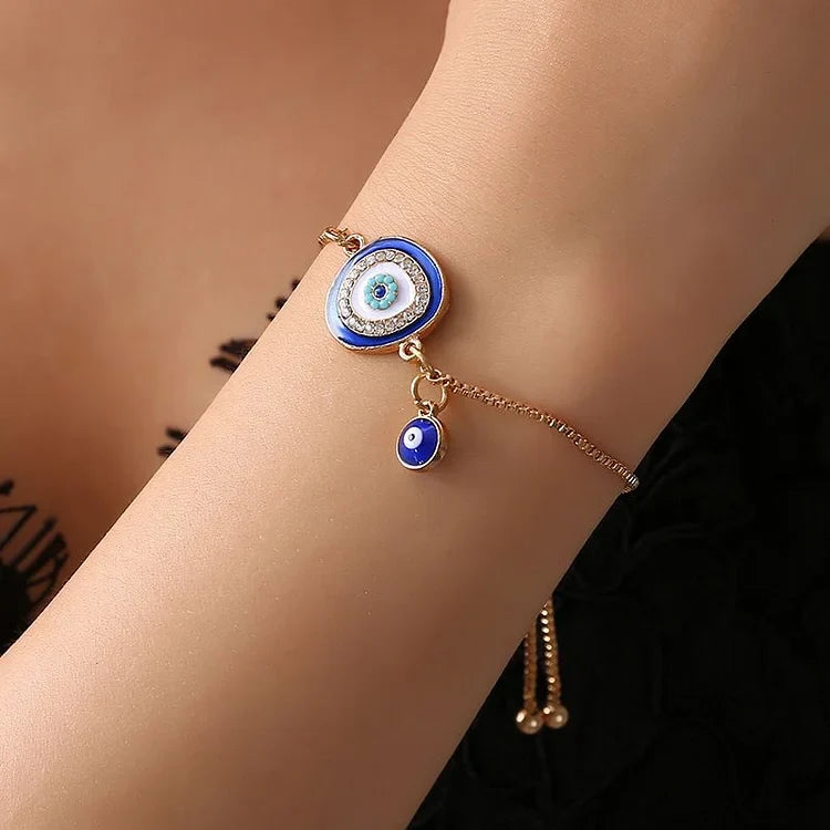 Close-up of a spiritual gold plated evil eye bracelet, featuring intricate ethnic details and a sparkling blue 'evil eye' charm.
