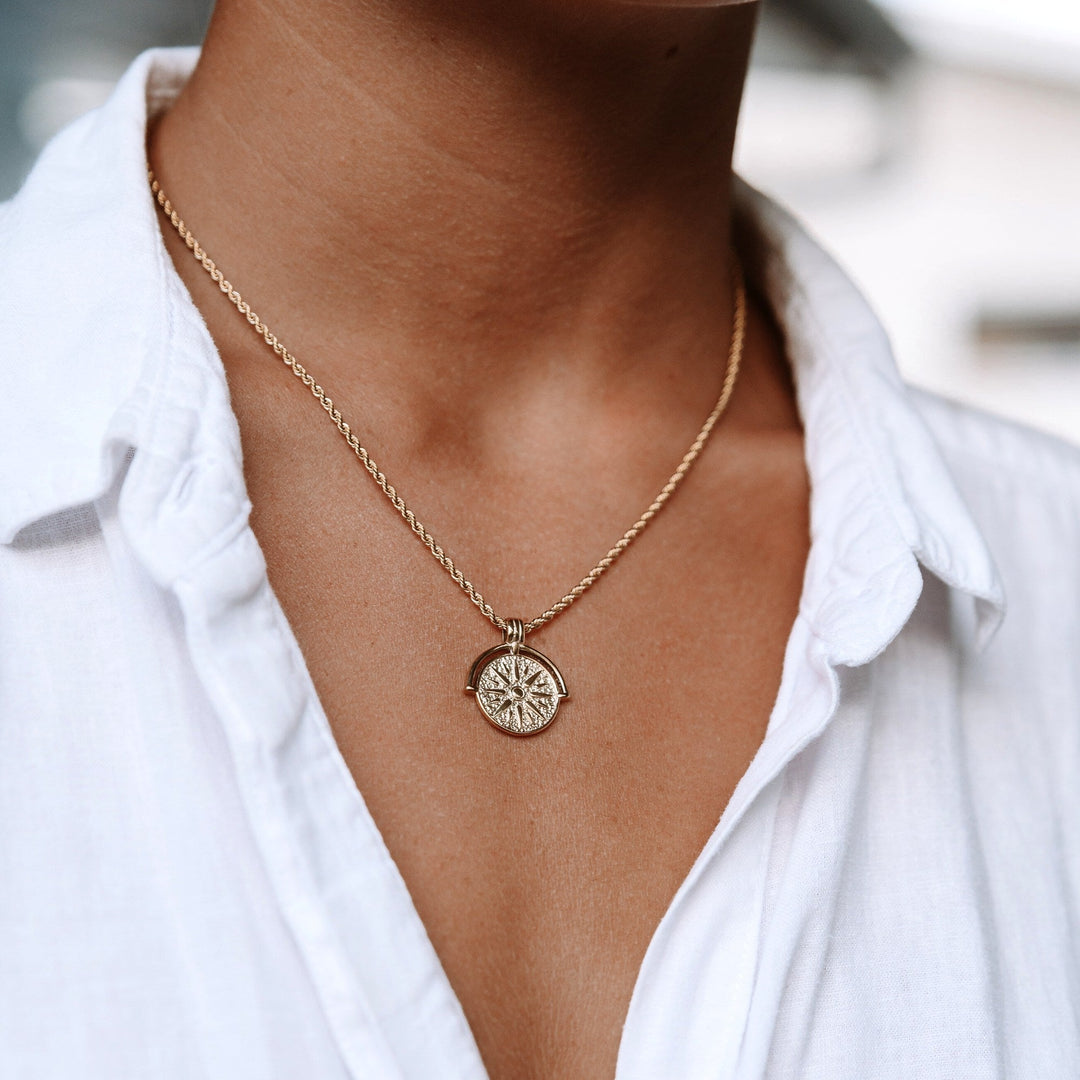 Women's gold radiant sun pendant necklace. Elegant celestial design for everyday wear.