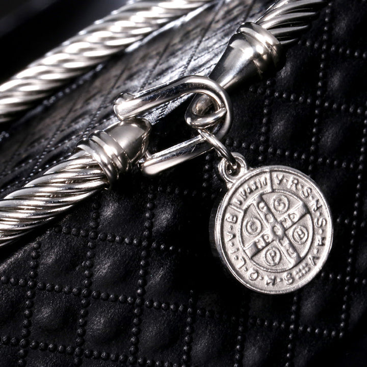 Close-up of a women's Saint Benedict charm bracelet, showcasing detailed gold and silver metals