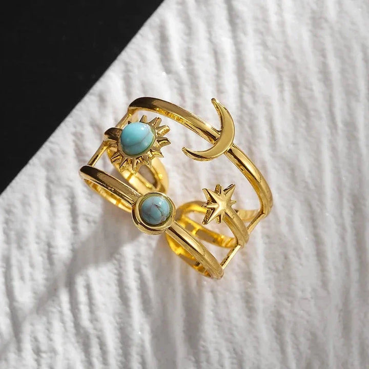 Close-up of a women's adjustable celestial sunburst star ring, gold tone stainless steel & turquoise.