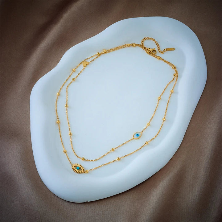 Elegant women's gold tone layered necklace featuring a protective evil eye pendant, modern fashion jewelry.