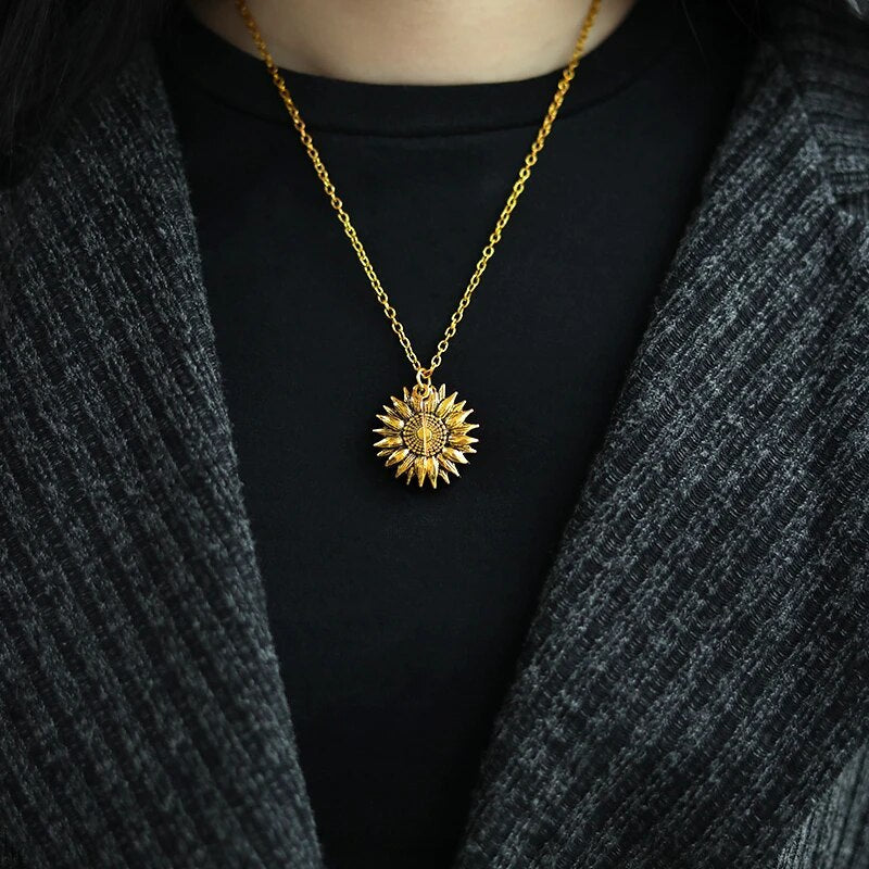 Close-up of gold tone 'You're My Sunshine' sunflower locket, women's sentimental jewelry.