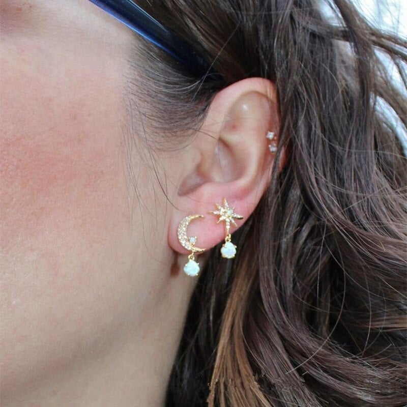 Close-up of women's delicate golden moon & star earrings, featuring luminous opal gems, elegant gift.