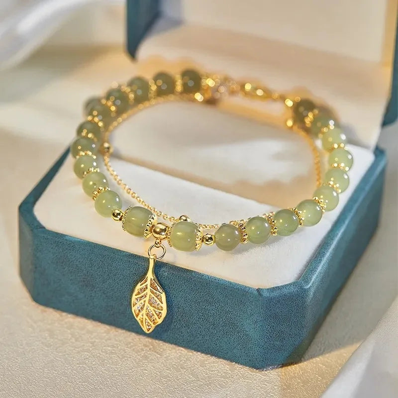 Smooth Hetian Jade beads with a polished gold accent charm on a women's adjustable gemstone bracelet, fine jewelry.