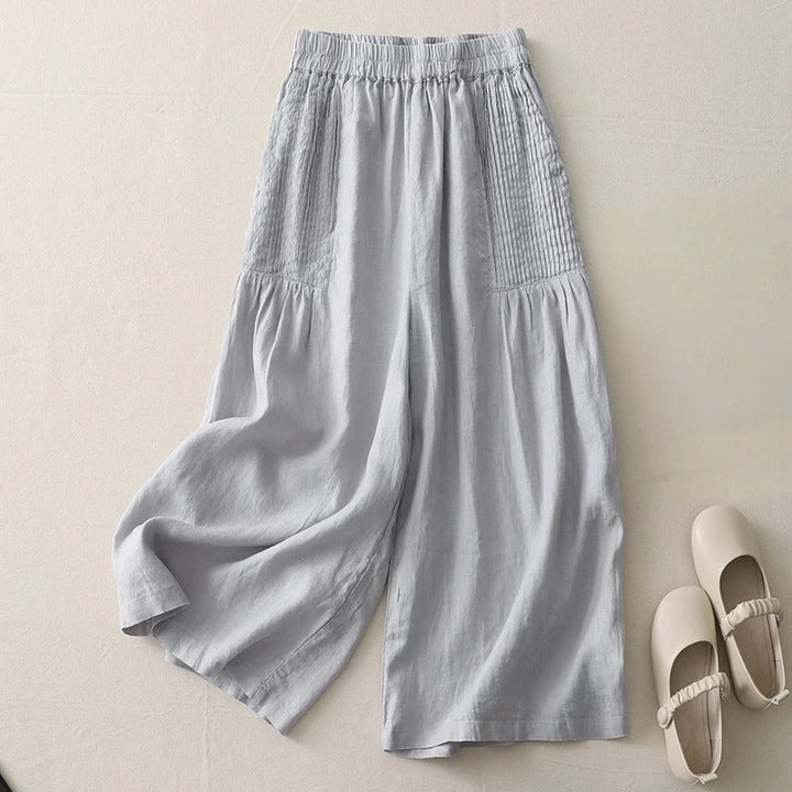 Stylish light gray pintucked wide-leg trousers for women. Flowy, high-waist design offers comfort & chic versatility.