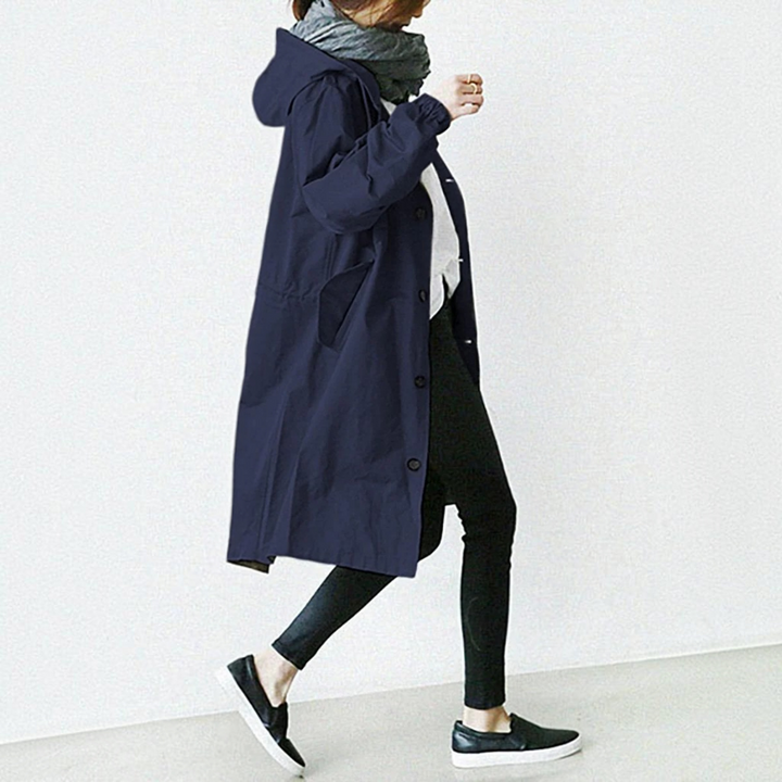 Woman wearing a hooded waterproof trench coat, stylish long raincoat for urban all-season fashion.
