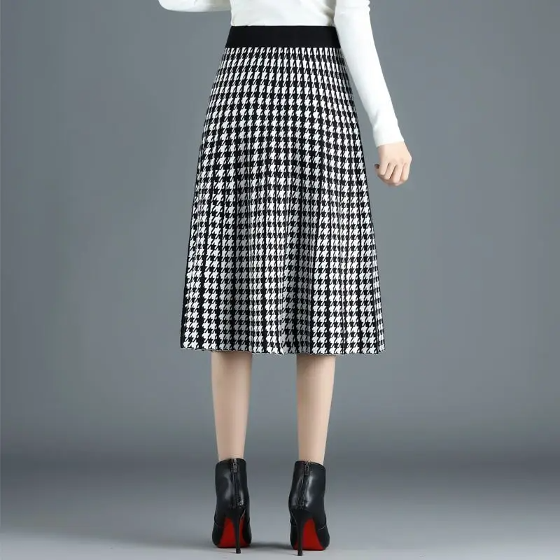 Chic women's houndstooth A-line midi skirt with pleats. Sophisticated high-waist design, versatile for office or fall.