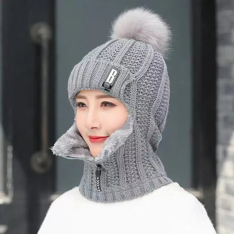 Warm women's knitted balaclava, a practical winter hat and face covering with a cute pompom for outdoor activities.