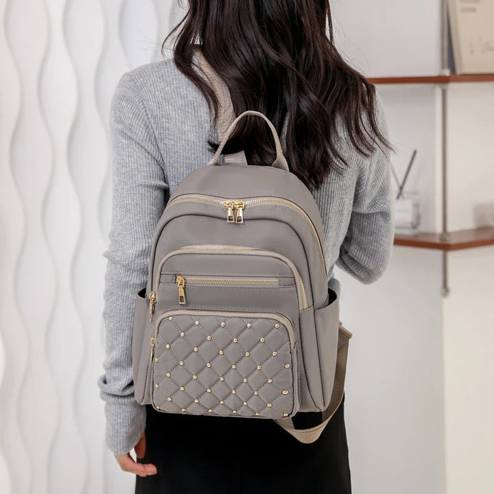 Stylish women's lightweight nylon backpack next to a cafe. Versatile water-resistant bag for daily carry & urban adventures.