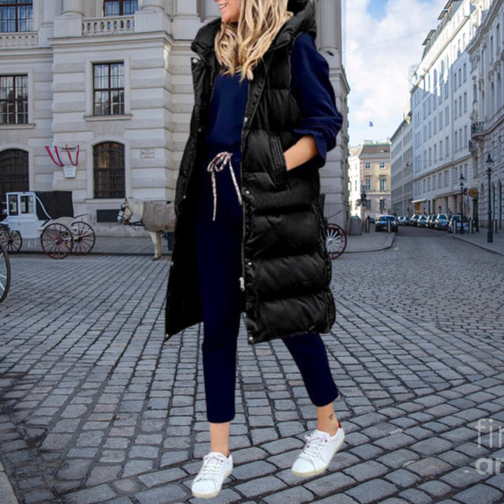 Women's hooded long vest, a versatile layering piece with padding & pockets for winter outerwear.