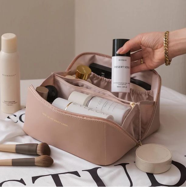 Woman holding BelleVault Luxe travel makeup bag, perfect portable storage for cosmetics & toiletries.