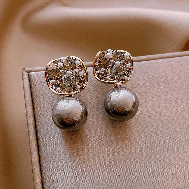 Women's gray and taupe pearl earrings featuring sparkling crystals, a luxurious and chic jewelry piece.