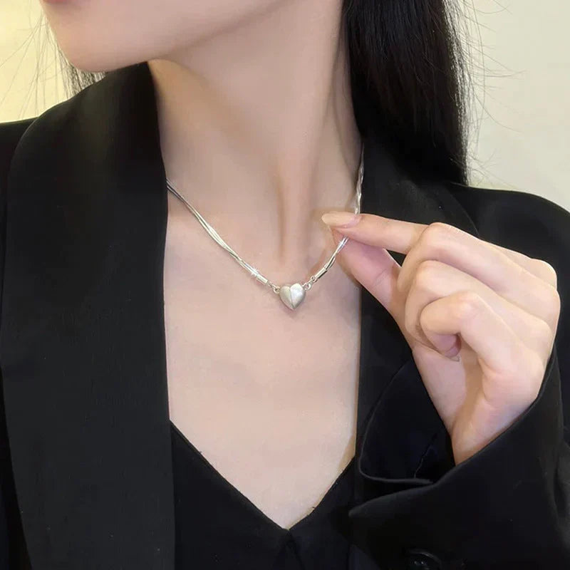 Side view of women's sterling silver magnetic love heart pendant necklace, adjustable chain, delicate jewelry.