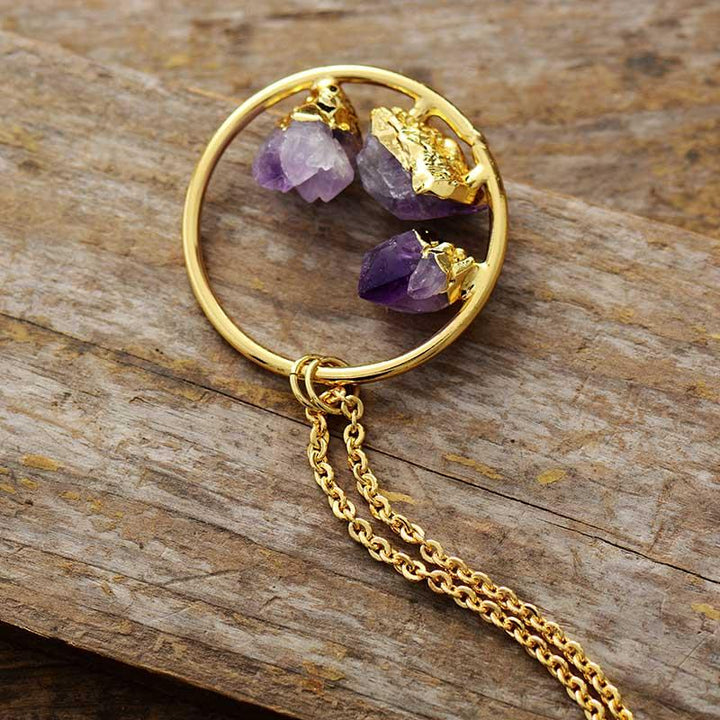 Close-up of a raw amethyst crystal gemstone pendant on a delicate silver-plated chain, minimalist women's jewelry.