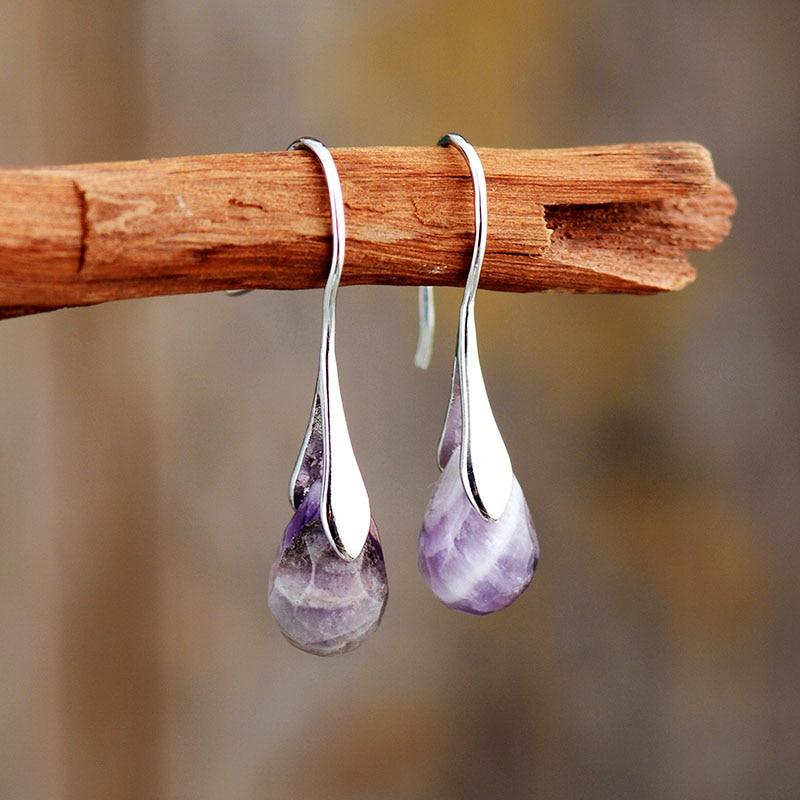 Close-up of women's natural gemstone dangle earrings, sterling silver with vibrant amethyst and red jasper stones.