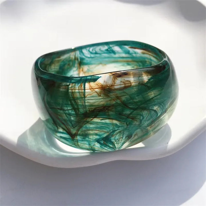 Close-up of a women's irregular acrylic bangle bracelet featuring a stunning organic marble design.