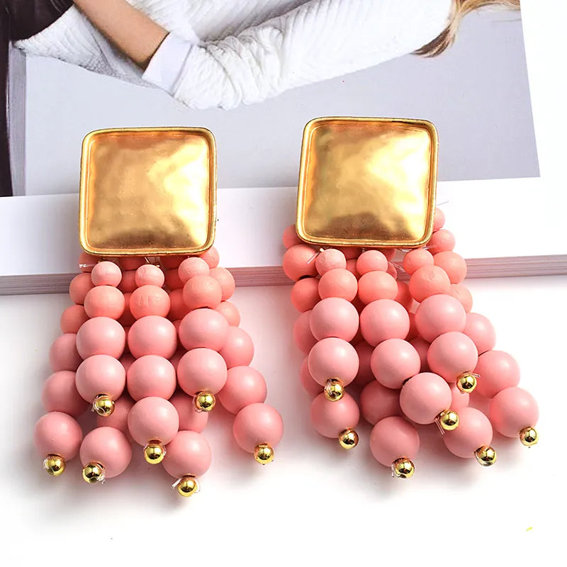 Artisan pearl-shaped wooden chain drop earrings. Handmade natural women's jewelry, a unique fashion accessory.