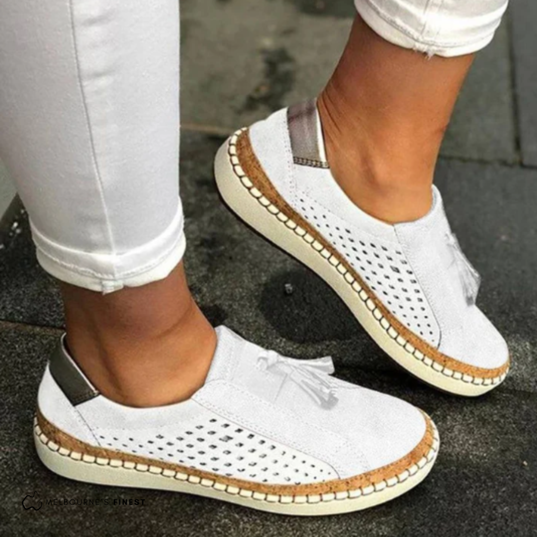 Women's perforated slip-on loafers with decorative tassel detail, offering comfortable & casual everyday style.