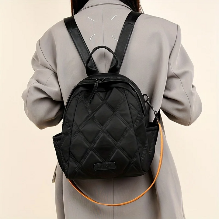 Women's quilted convertible backpack with discreet pocket. Functions as shoulder or crossbody bag.
