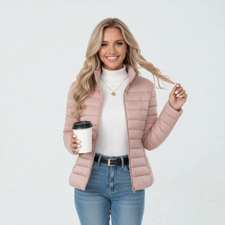 Woman walking in a warm quilted jacket. Stand collar, full zip for everyday wear & winter comfort.