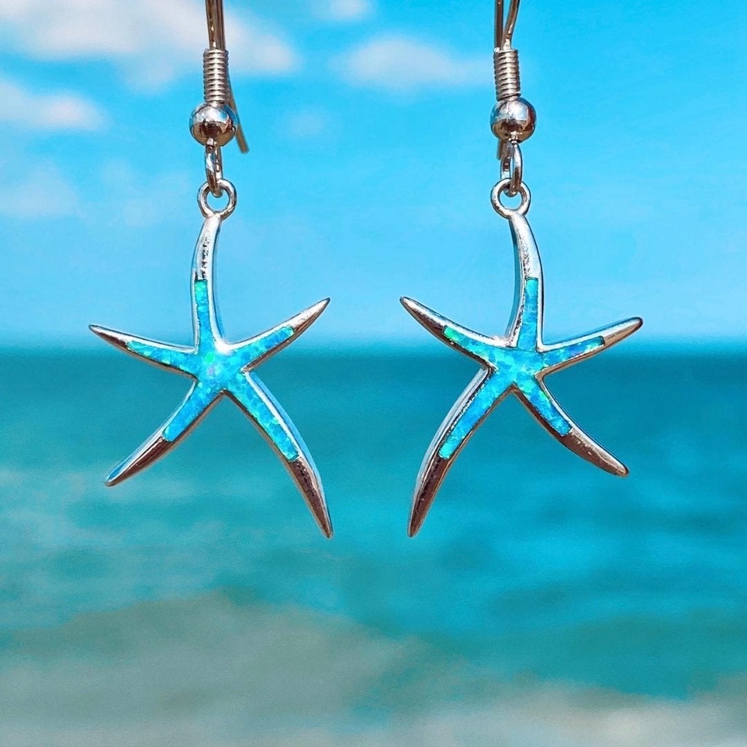 Women's silver starfish earrings with shimmering blue opal inlay, elegant ocean-inspired jewelry for coastal style.