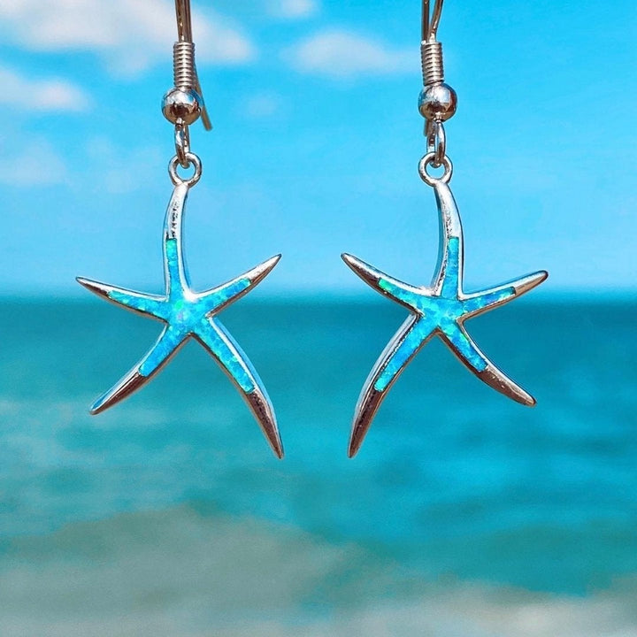 Women's silver starfish earrings with shimmering blue opal inlay, elegant ocean-inspired jewelry for coastal style.