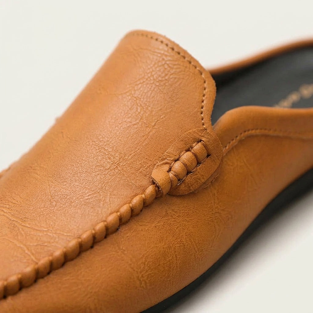Black women's slip-on mules with elegant hand-stitched accents. Perfect comfortable flat shoes for summer fashion.
