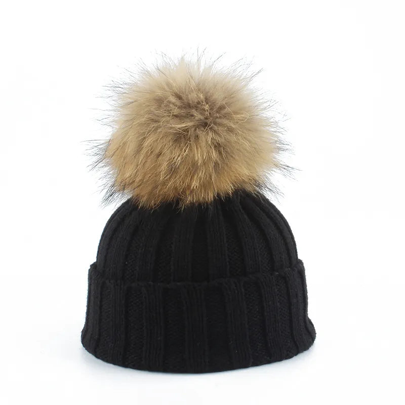 Women's soft pink knit winter beanie with large faux fur pom-pom, perfect for cold weather fashion