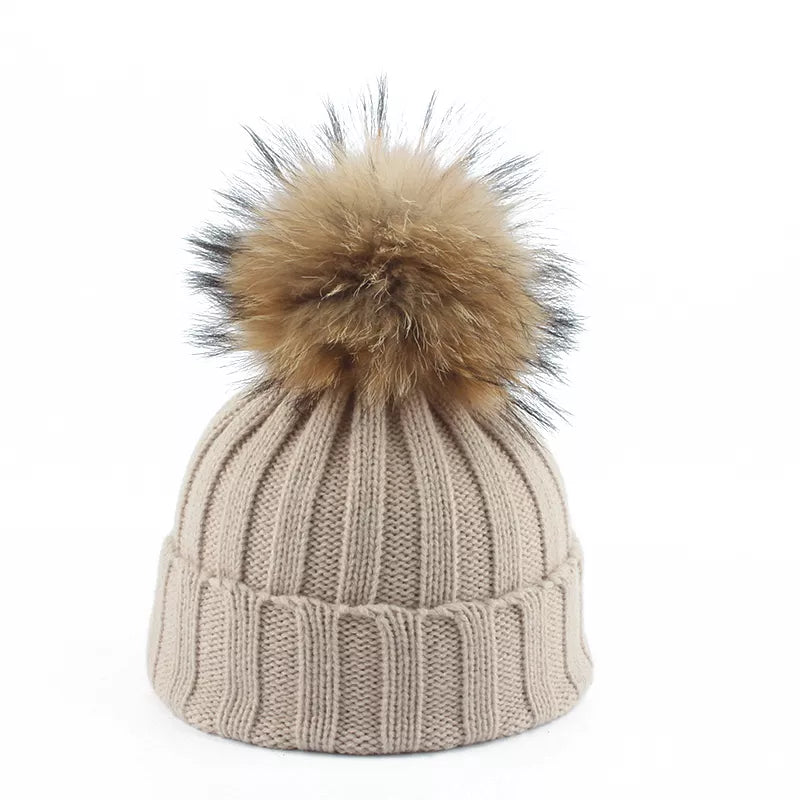 Close-up of a women's black knit winter beanie featuring a luxurious faux fur pom-pom detail