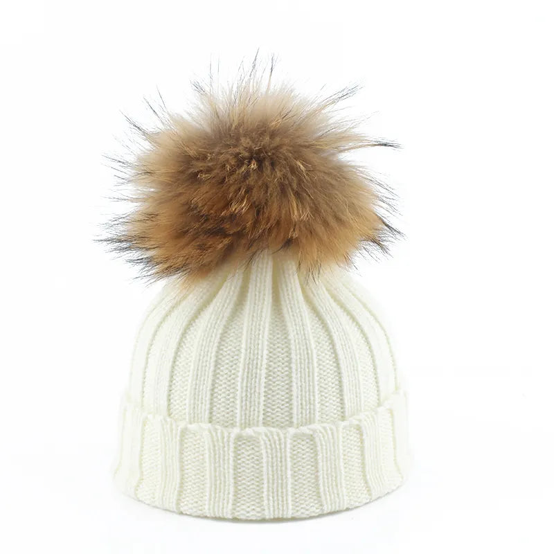 Side view of a women's rich burgundy knit winter beanie showcasing its plush faux fur pom-pom