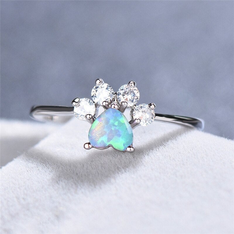 Close-up of an elegant women's silver ring featuring a vibrant opal and brilliant zirconia. Perfect gemstone jewelry.