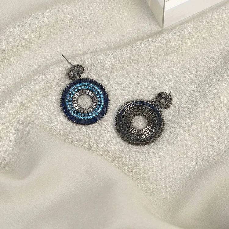 Close-up of women's sterling silver evil eye stud earrings, with vibrant blue and white enamel detailing
