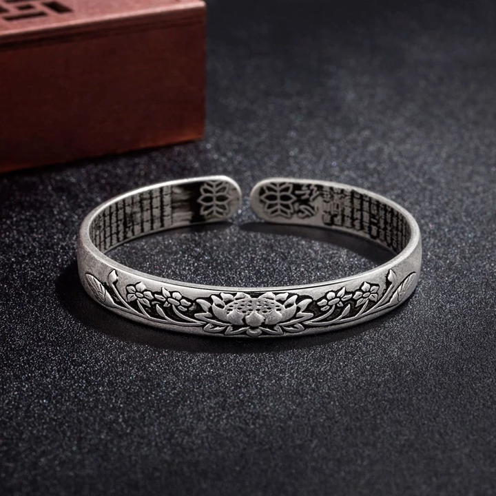 Close-up of a delicate adjustable silver lotus charm bracelet for women.