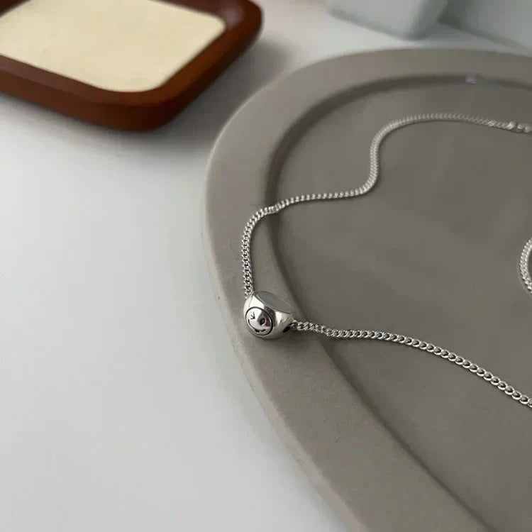 Women's sterling silver necklace with a playful double-sided smiley charm. Stylish fashion jewelry for women.