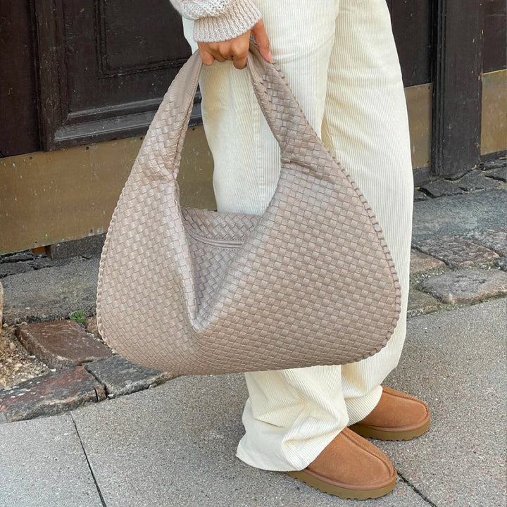 Close-up of braided texture on women's woven shoulder bag, spacious and versatile handbag.