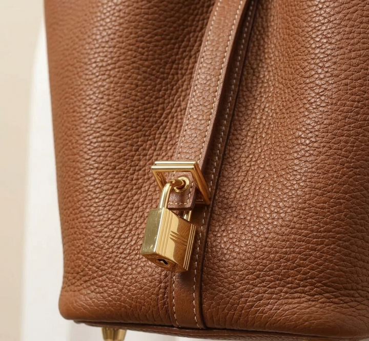 Full view of a modern women's leather bucket bag, featuring a comfortable shoulder strap and elegant design.