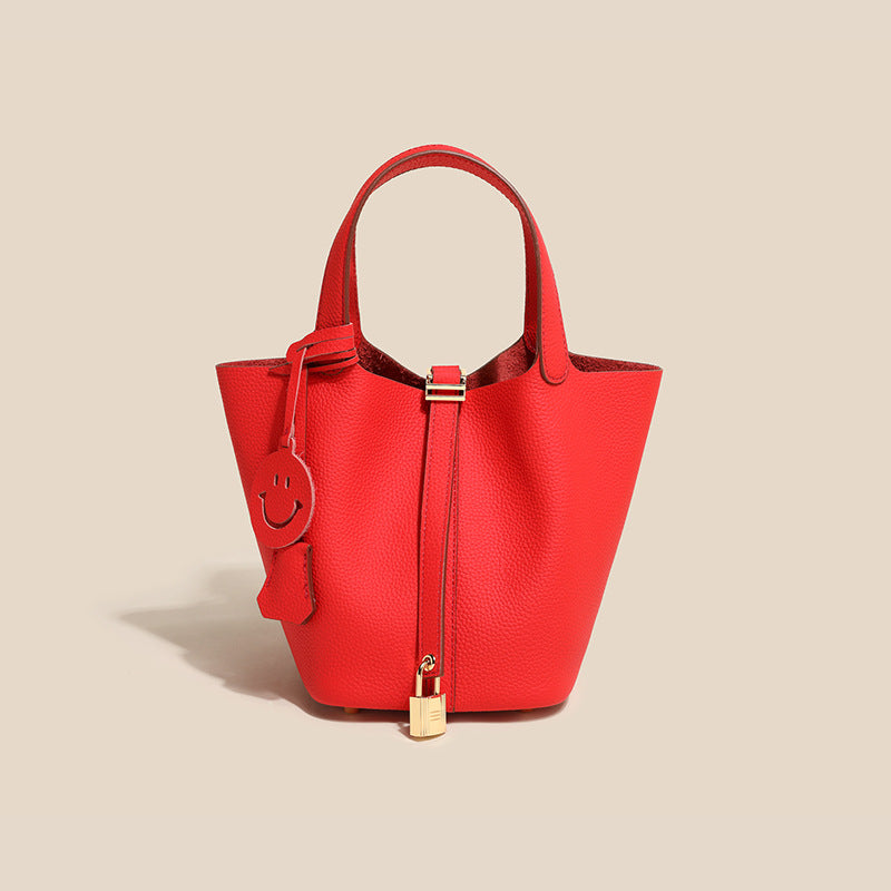 Detail shot of the gold hardware and supple cowhide leather on a women's bucket bag.