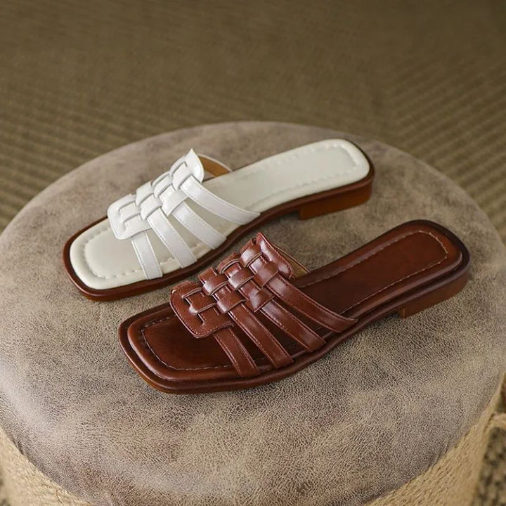 Stylish women's white & brown flat slide sandals, featuring geo cutouts & cushioned comfort.