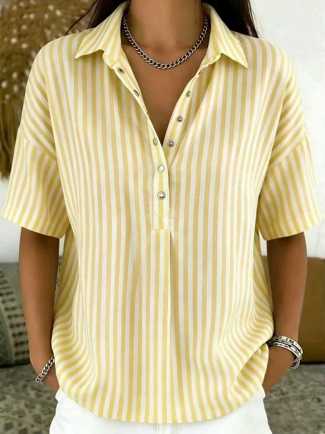 Relaxed fit women's short sleeve blouse featuring a trendy vertical stripe pattern and half-button detail.