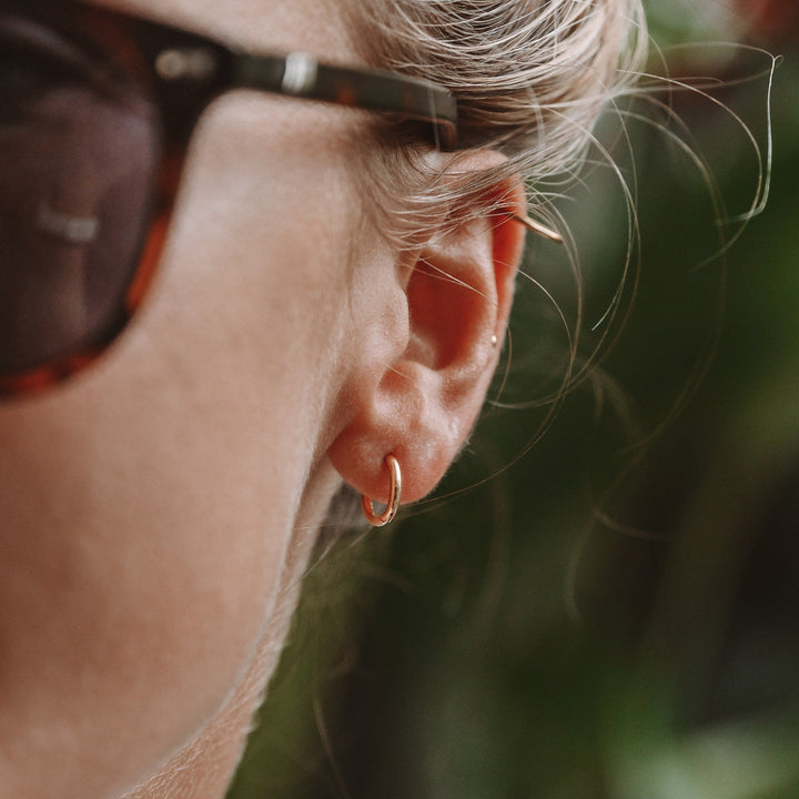 Women's subtle gold mini hoop earrings, hypoallergenic for sensitive ears.