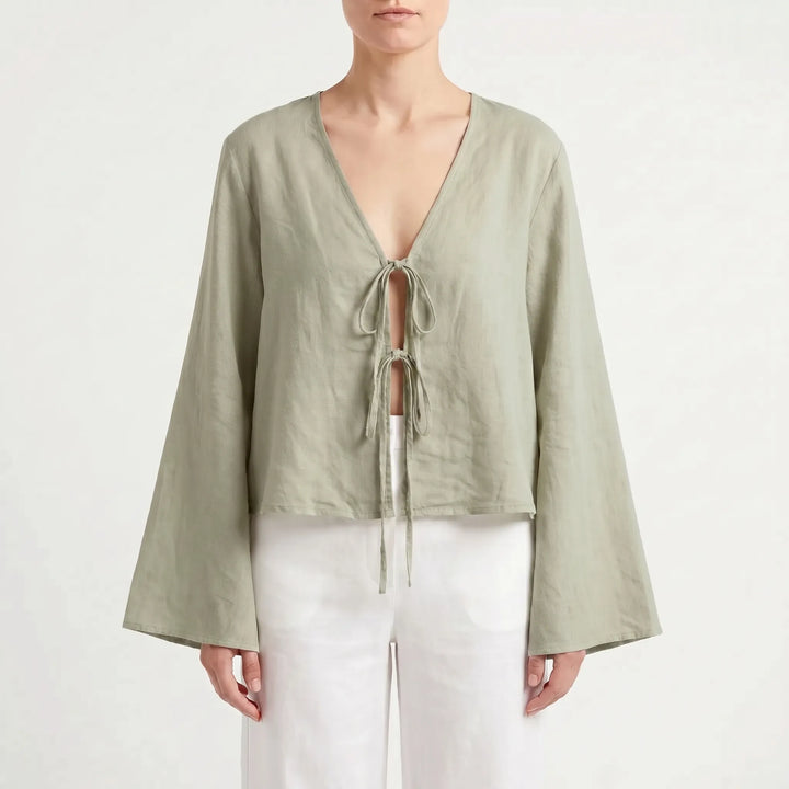 Close-up of the stylish front-tie detail on a women's relaxed fit summer blouse. Casual long-sleeve top fashion.