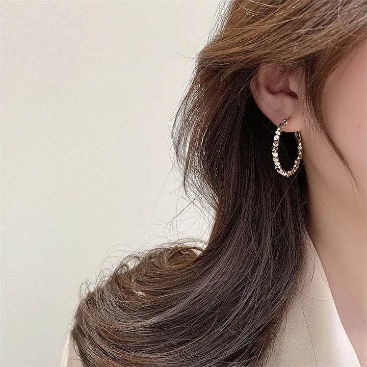 Gold faceted hoop earrings, a versatile and minimalist women's jewelry piece.