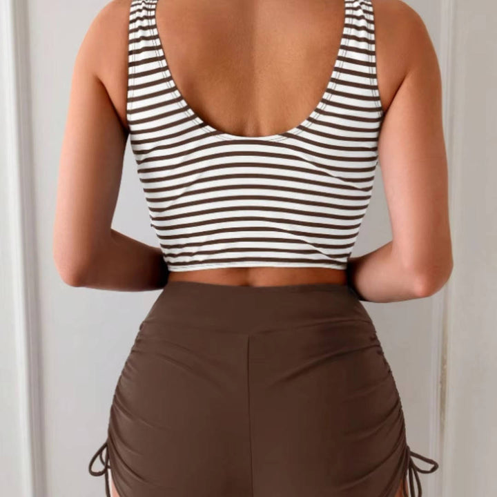 Woman posing confidently in a tummy control, high waisted tankini swimsuit with a twist front.