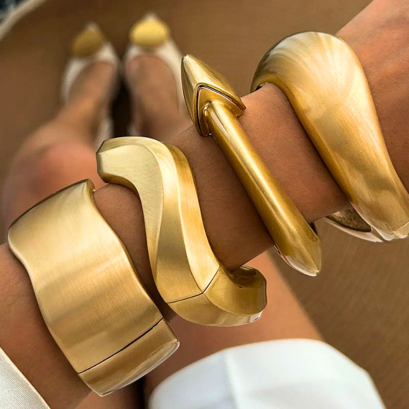 Set of women's vintage gold cuff bangles, featuring brushed metal and elegant organic shapes.
