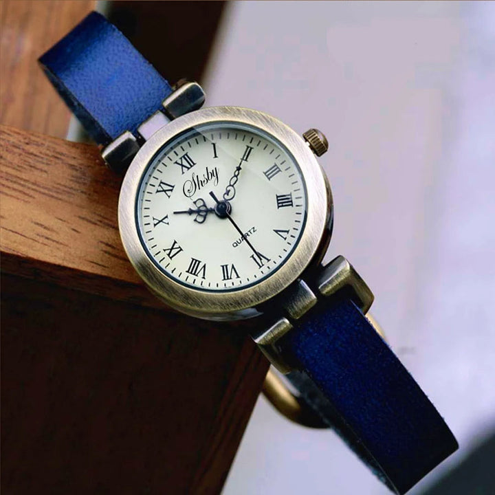 Close-up of a women's vintage-style quartz watch face with Roman numerals & leather strap.