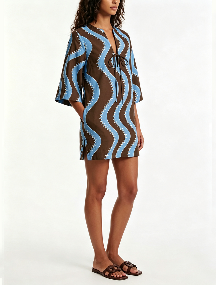 Close-up of blue & black wave print mini dress, showing collared neckline & button details. Breezy summer beachwear.