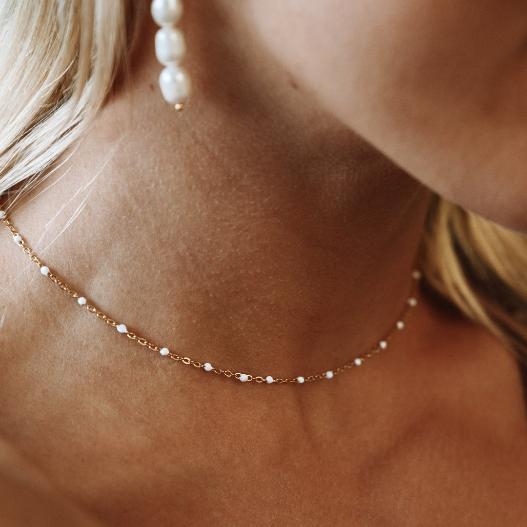 Delicate women's choker necklace featuring pristine white enamel beads.
