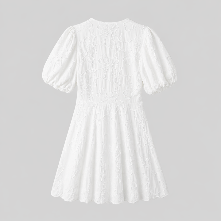 Full shot of white textured floral midi dress. Features puff sleeves, V-neck, and delicate A-line flow, a chic summer dress.